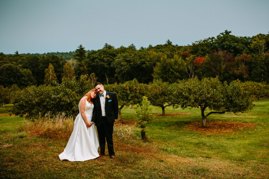 A couple cuddles during their wedding at Union Lake Orchard in New Hampshire