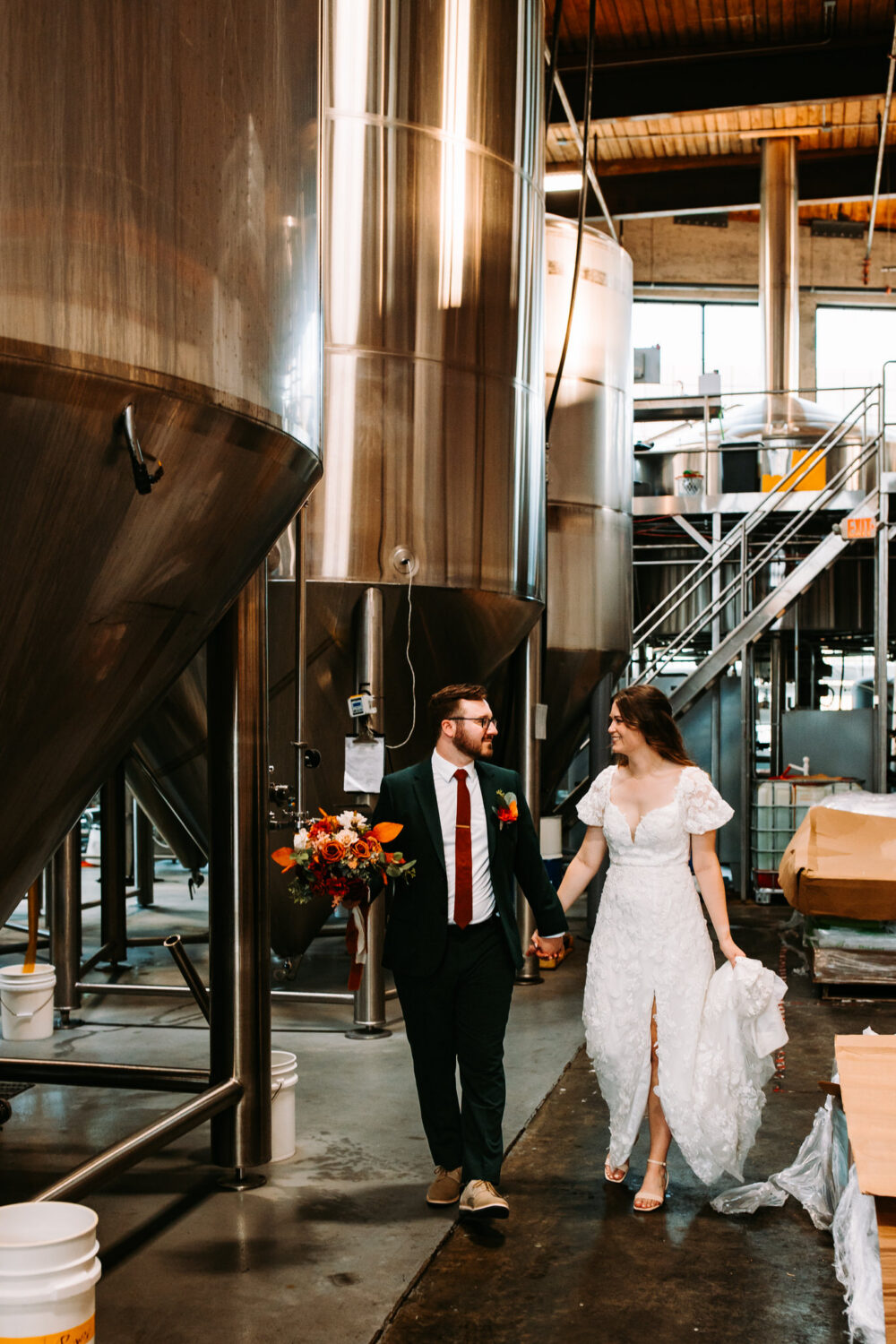 A couple walks around the beer kegs at their wedding at The Guild Pawtucket in Rhode Island