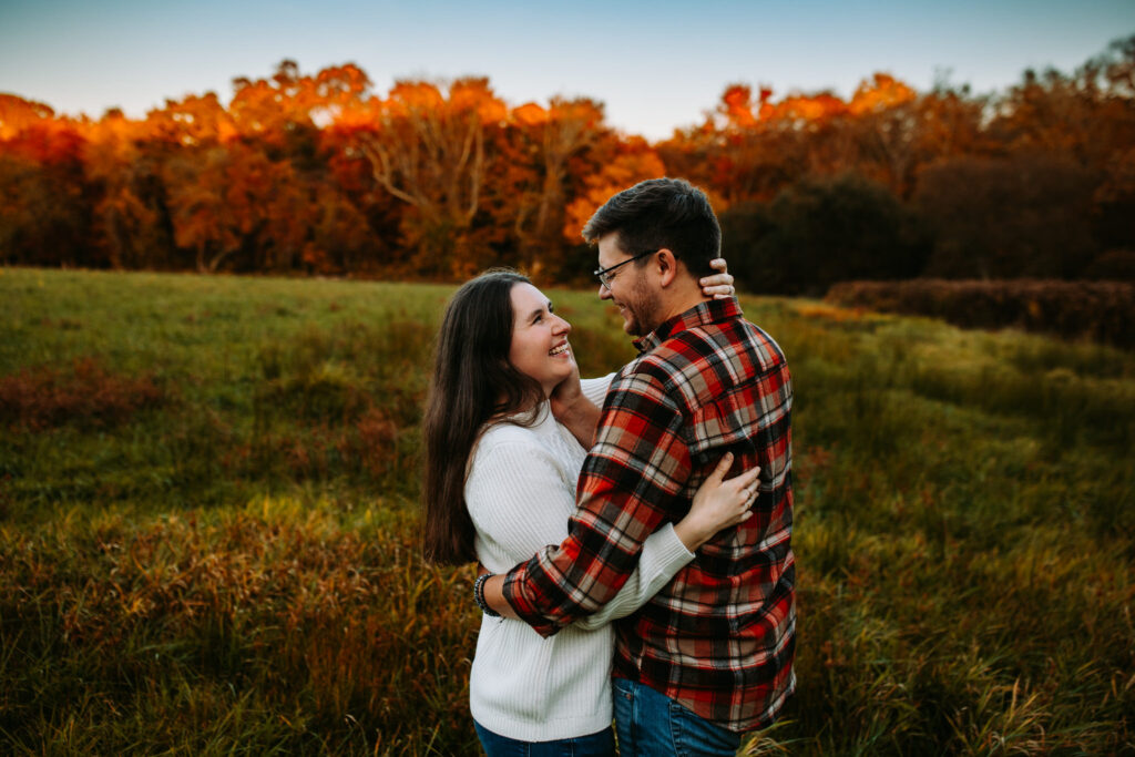 A couple embraces at their engagement session at Weetamoo Woods in Tiverton, Rhode Island