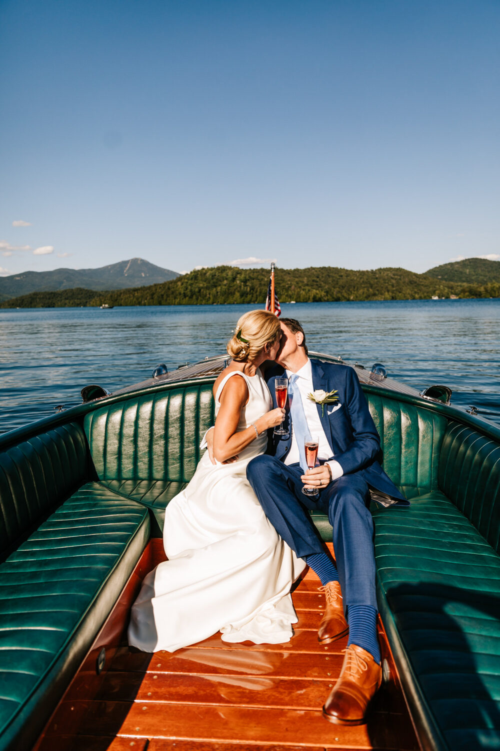 Bridge and Groom kiss on the boad at their micro-wedding at Lake Placid Lodge