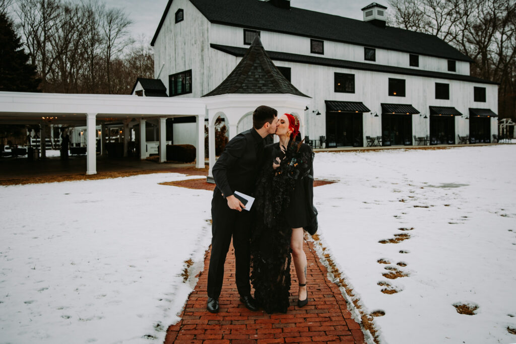 Bride and groom kiss along the walkway at their winter wedding at Five Bridge Inn in Massachusetts