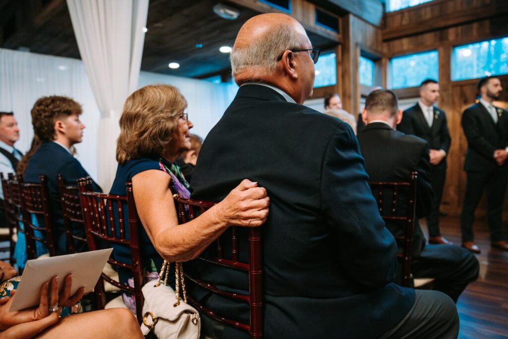 Candid moment of a guest gently placing her arm around her partner during the emotional ceremony