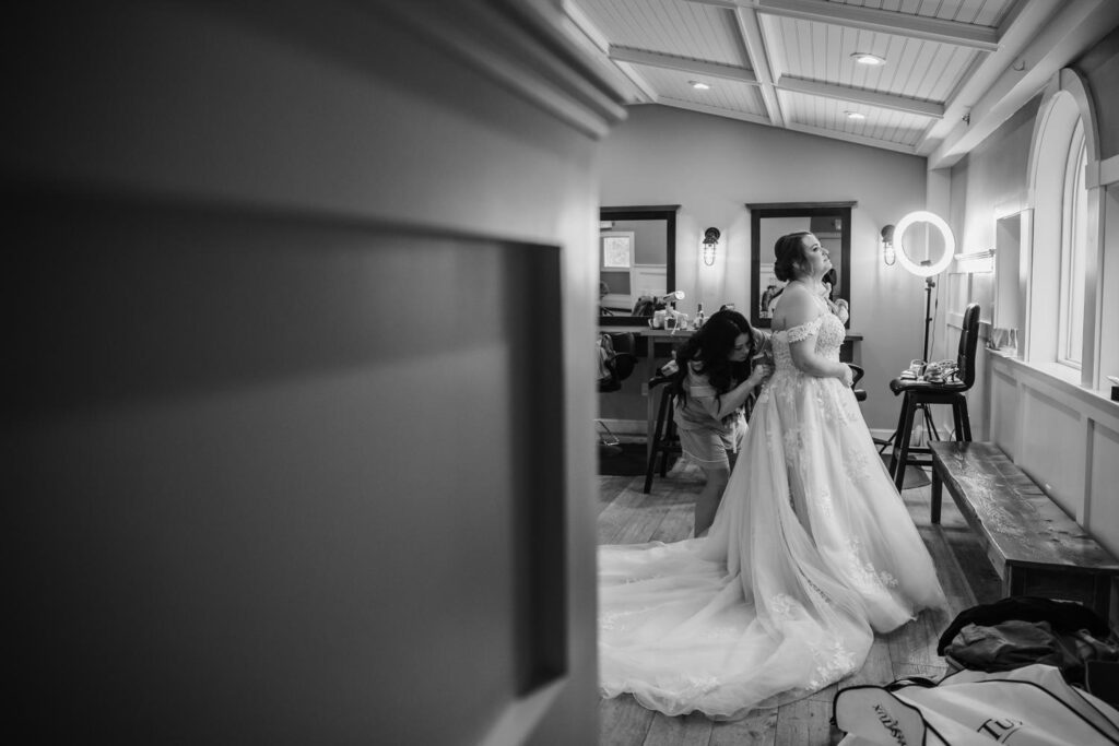 Candid black and white shot of bride walking down the hallway in her gown before the ceremony