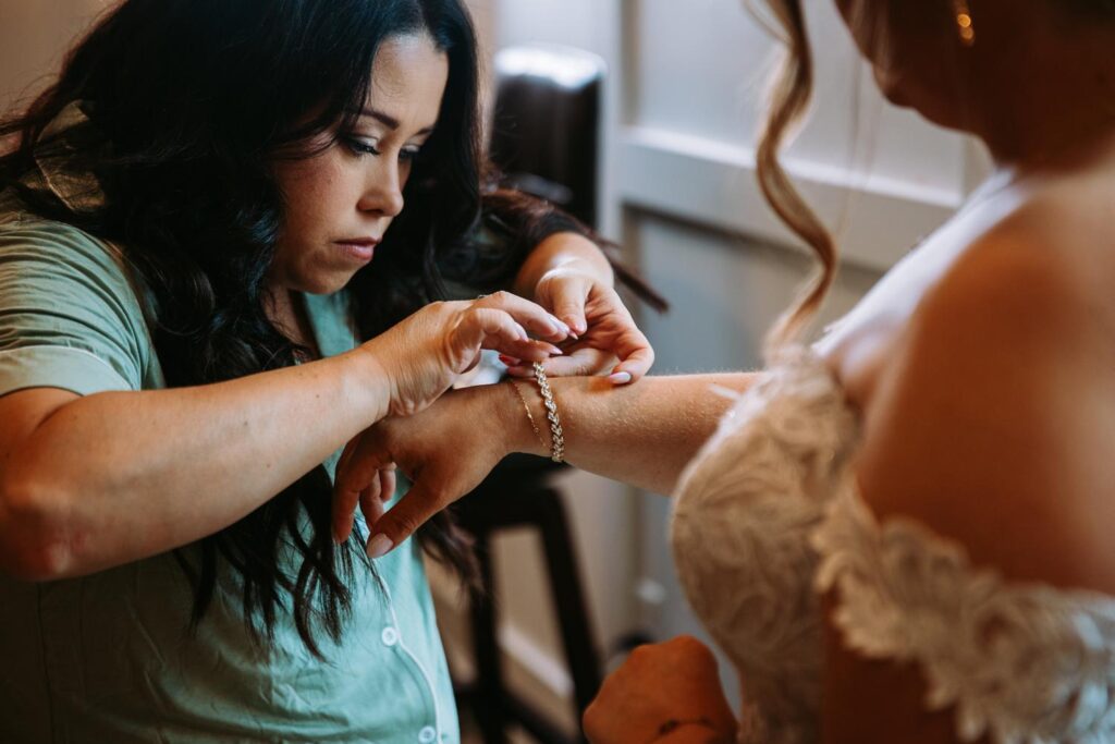 Close-up of bride getting bracelet fastened on her wrist during final getting ready moments