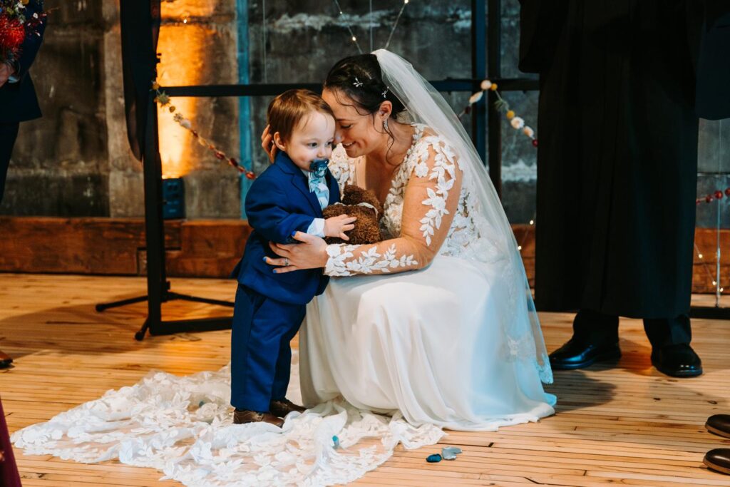 Bride kneels down to hug one of her sons during the ceremony.