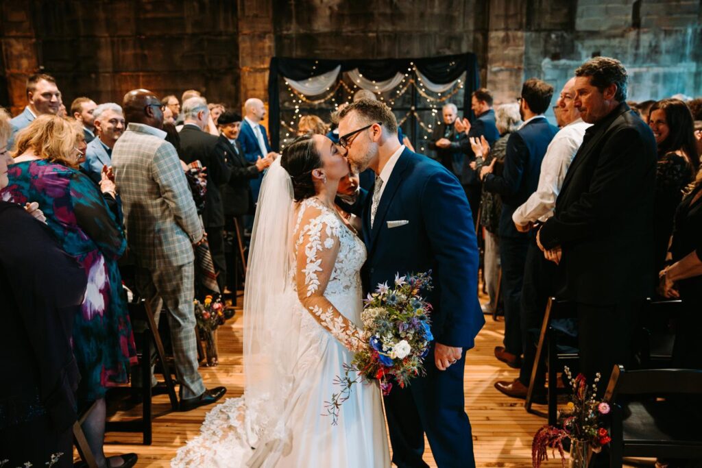 Bride and groom walking up the aisle, hand in hand, after being pronounced married.