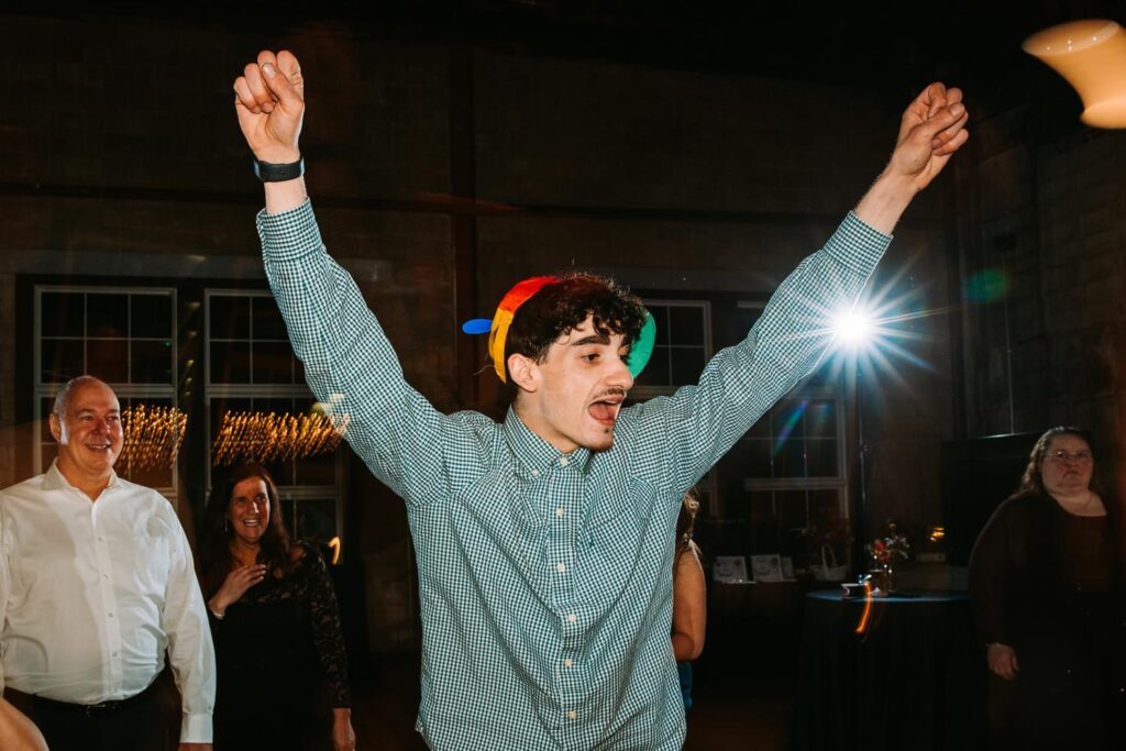 Young man with hands raised mid-dance on the lively dance floor at Olio.