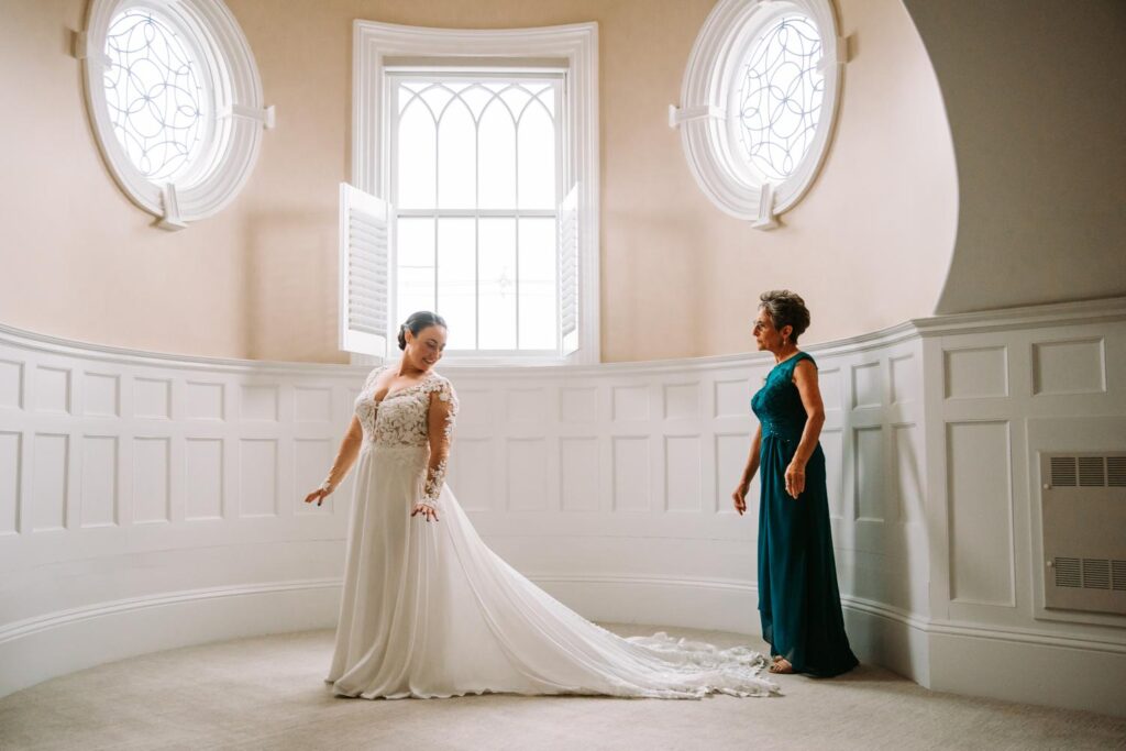 Bride’s mom standing in the soft window light before the ceremony begins.