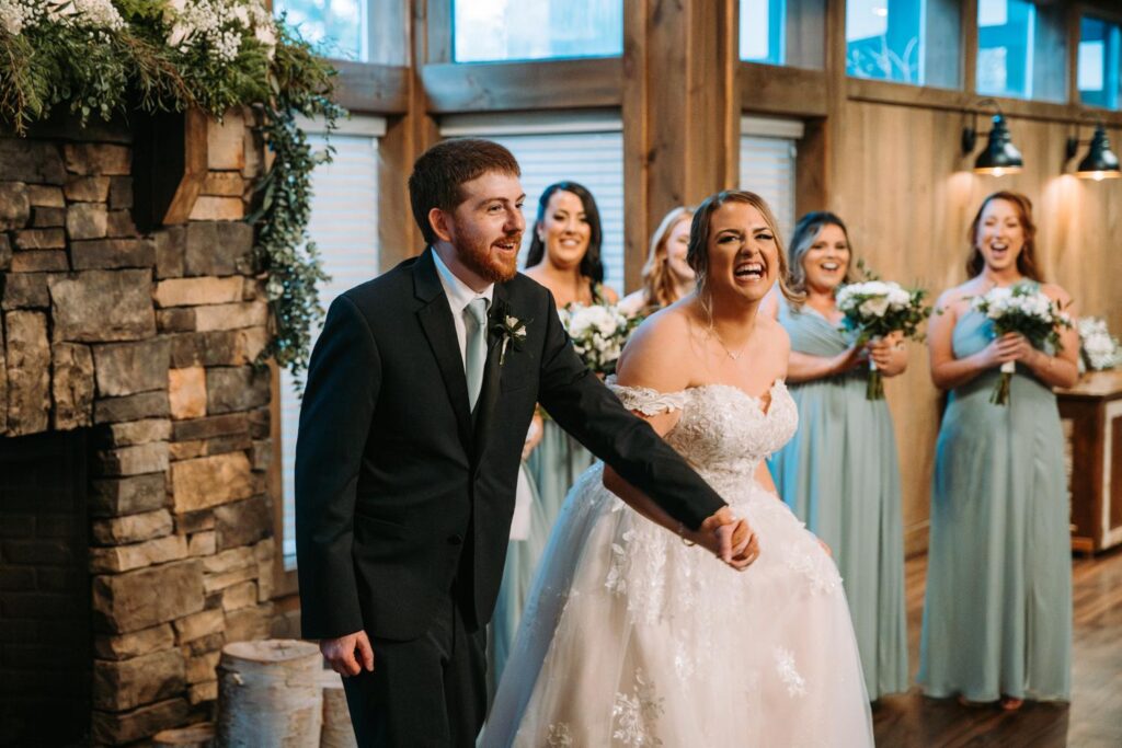 Bride and groom holding hands and soaking in the moment together in front of the stone fireplace