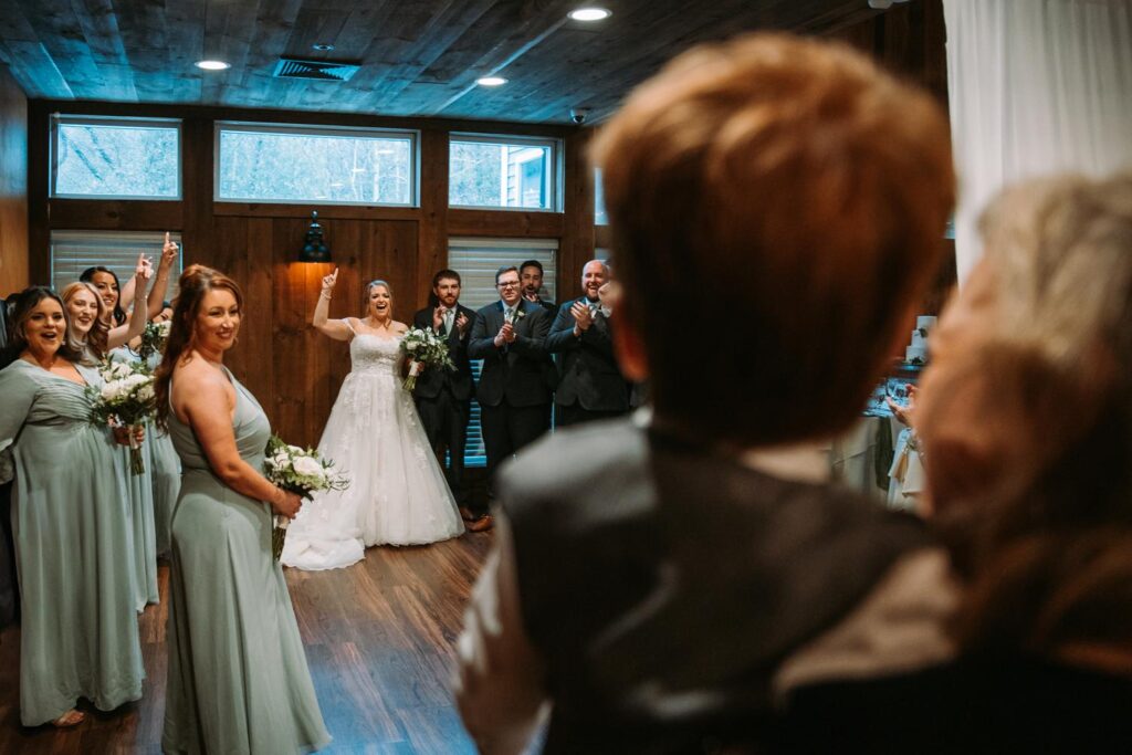 Candid moment of the bride laughing with her wedding party as guests react in the foreground