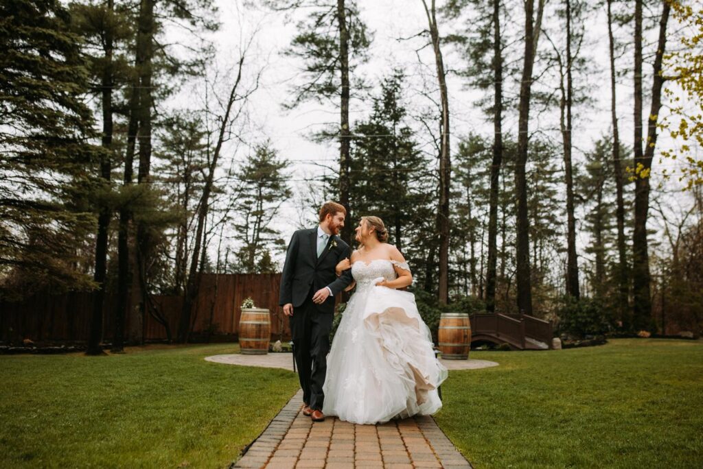 Bride smiling sweetly while standing in her full wedding gown surrounded by spring greenery