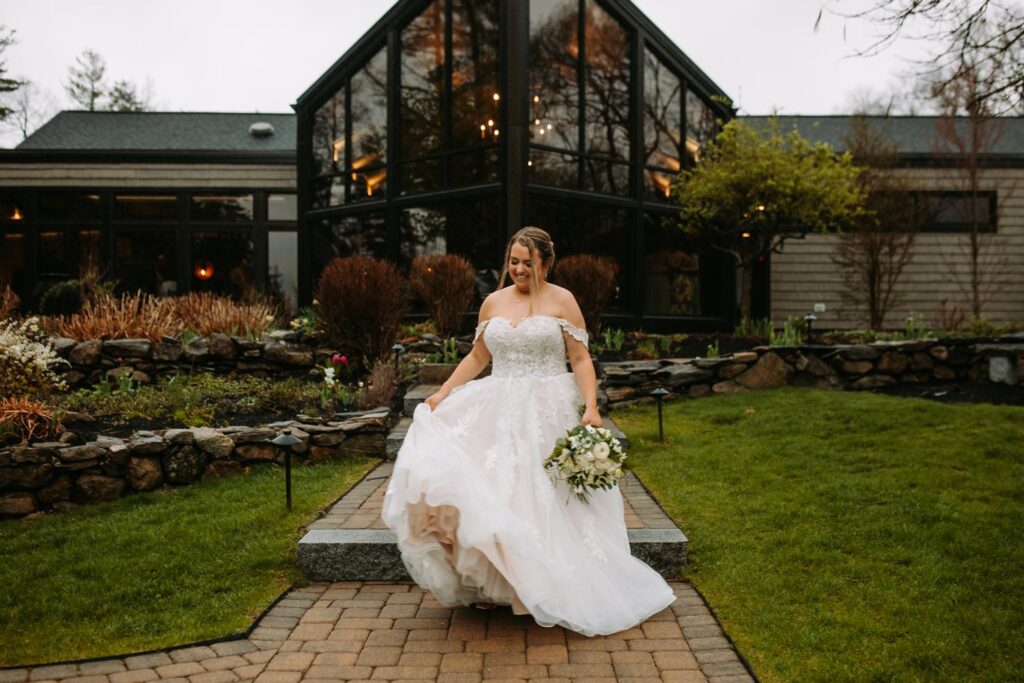 Bride sitting with her bouquet in front of Birch Wood Vineyards, surrounded by spring florals and moody skies