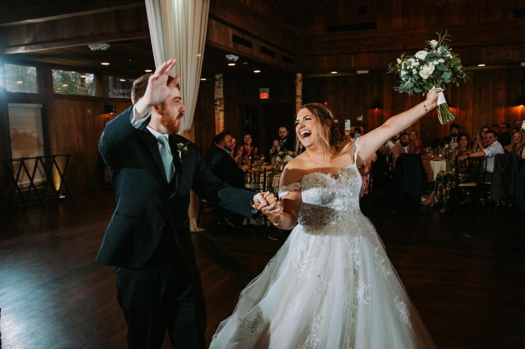 Bride and groom raising their arms in excitement during a fun, high-energy reception entrance