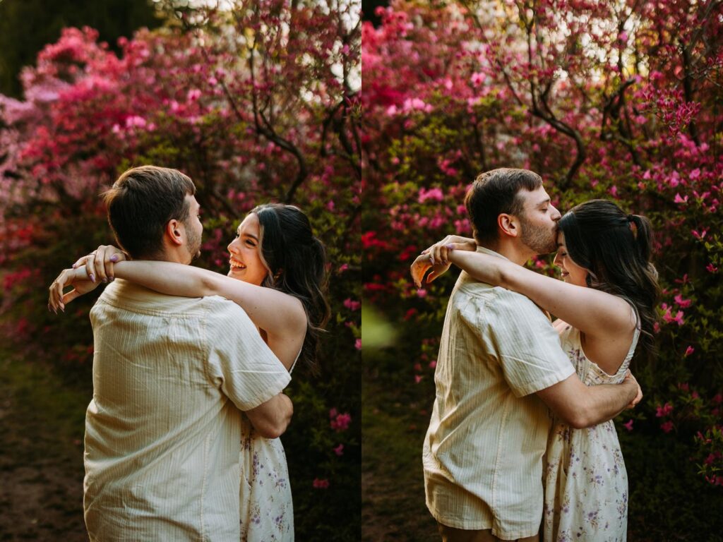 Couple wrapped in each other's arms, smiling beneath vibrant pink azaleas.