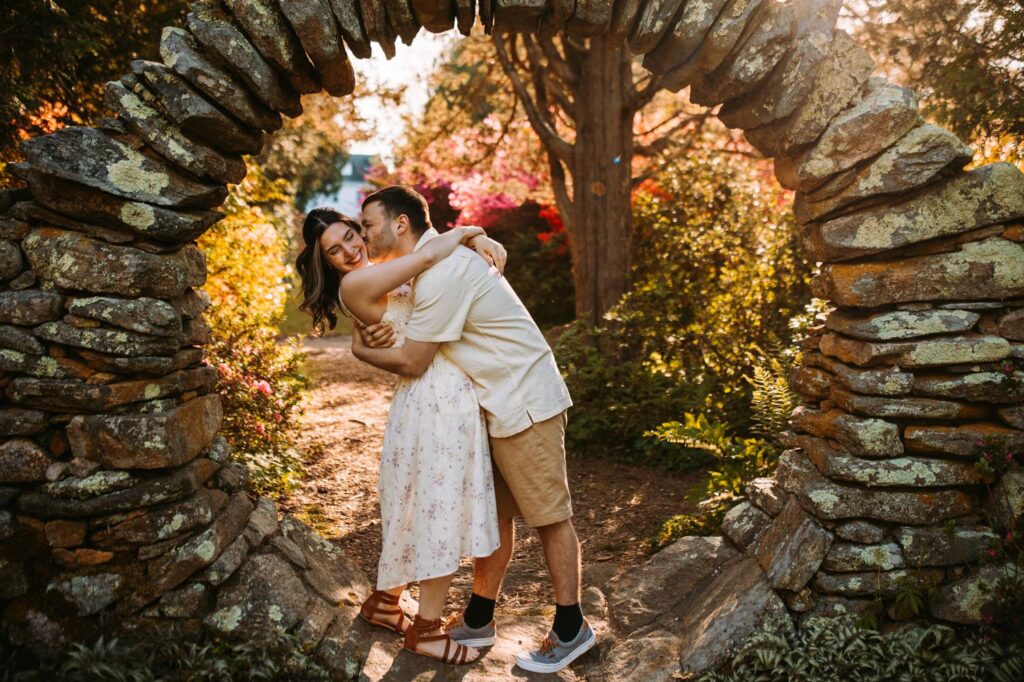 Couple sharing a kiss under the iconic stone arch at Kinney Azalea Garden.
