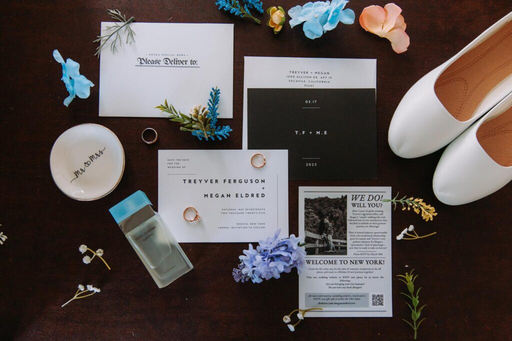 Flat lay of wedding invitation suite with white shoes and floral accents