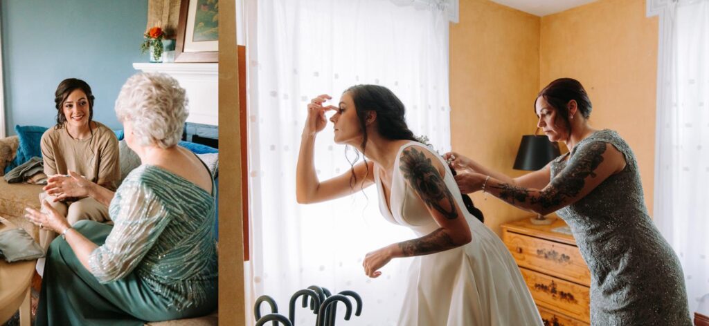 Bride adjusting makeup while bridesmaids offer support in warm farmhouse lighting.