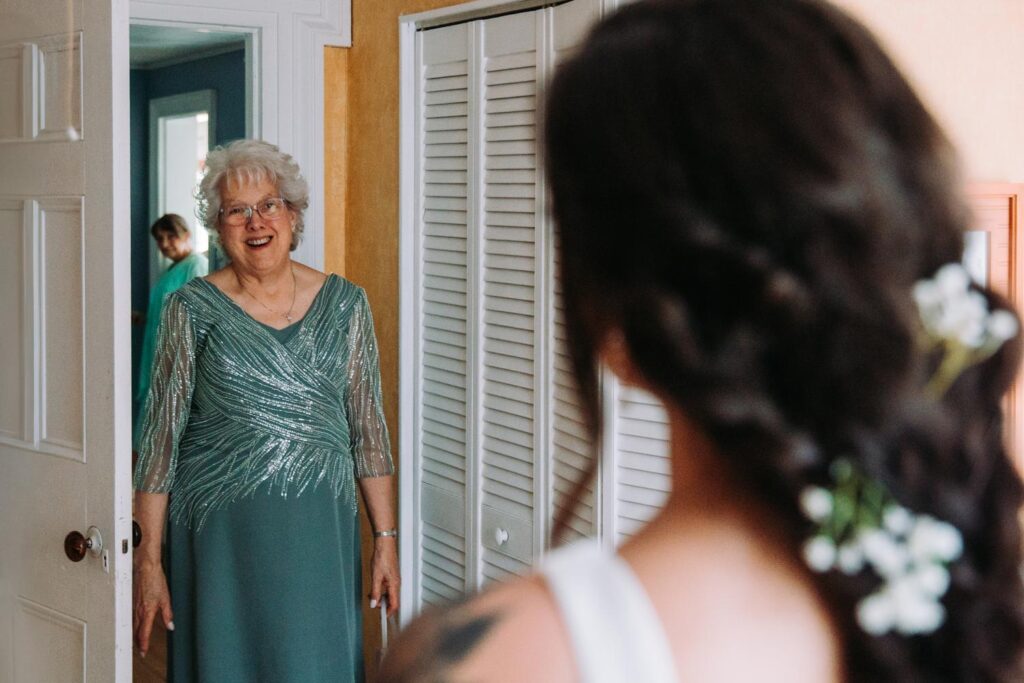 Bride smiling as her grandmother sees her in her wedding dress at Bluebird Farm in Medusa, NY.