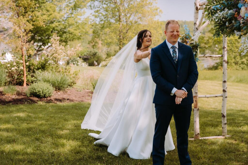 Bride walking up behind groom for their emotional first look at Bluebird Farm.