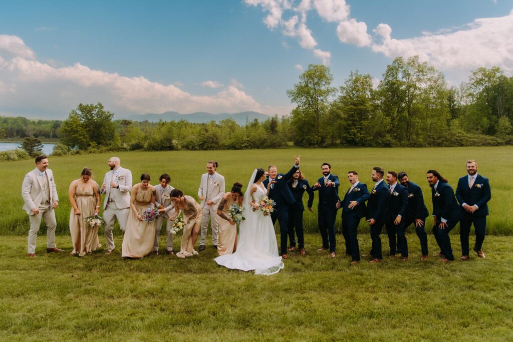 Full wedding party lined up outdoors with Catskill Mountains behind them.