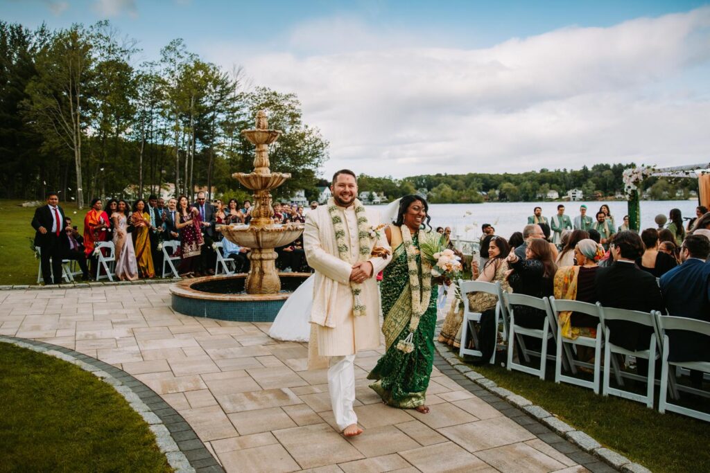 Couple walking down the aisle together as guests cheer after ceremony at Grandview Mendon Massachusetts Indian wedding