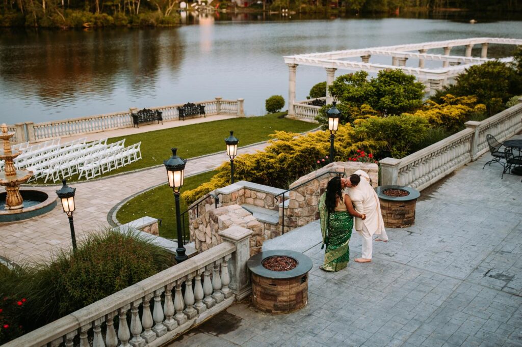 Couple holding hands walking across Grandview Mendon Massachusetts lawn during Indian wedding portraits