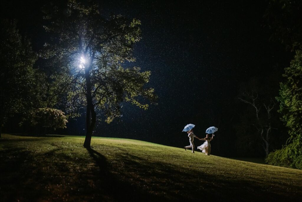A bride and groom running in the rain with clear umbrellas at their backyard wedding in Moodus, Connecticut