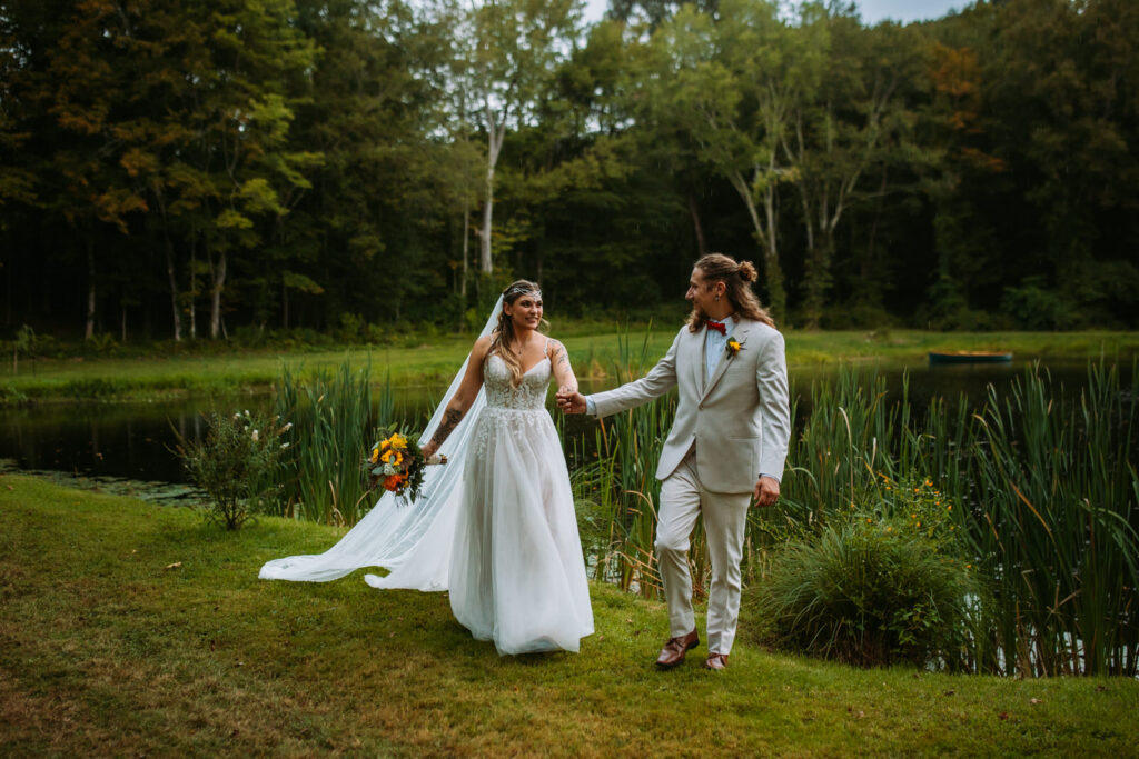 Bride and groom walk in front of a pond at a backyard wedding in Moodus, Connecticut
