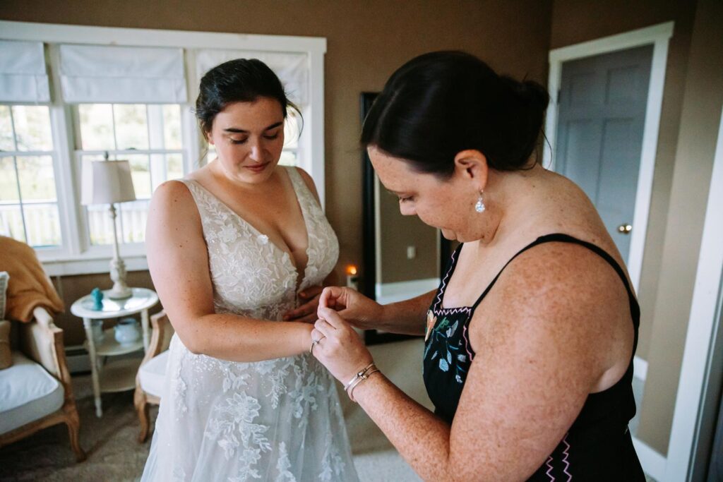 Bridesmaids helping bride get ready at The Barn on Gobeille Farm wedding in Sharon Vermont