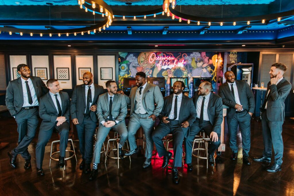 Groomsmen pose in the colorful cocktail hour bar area at the wedding venue Oceanview of Nahant