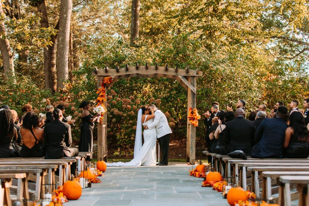 A bride and groom share their first kiss in the outdoor ceremony space in the Garden at The Hops Company
