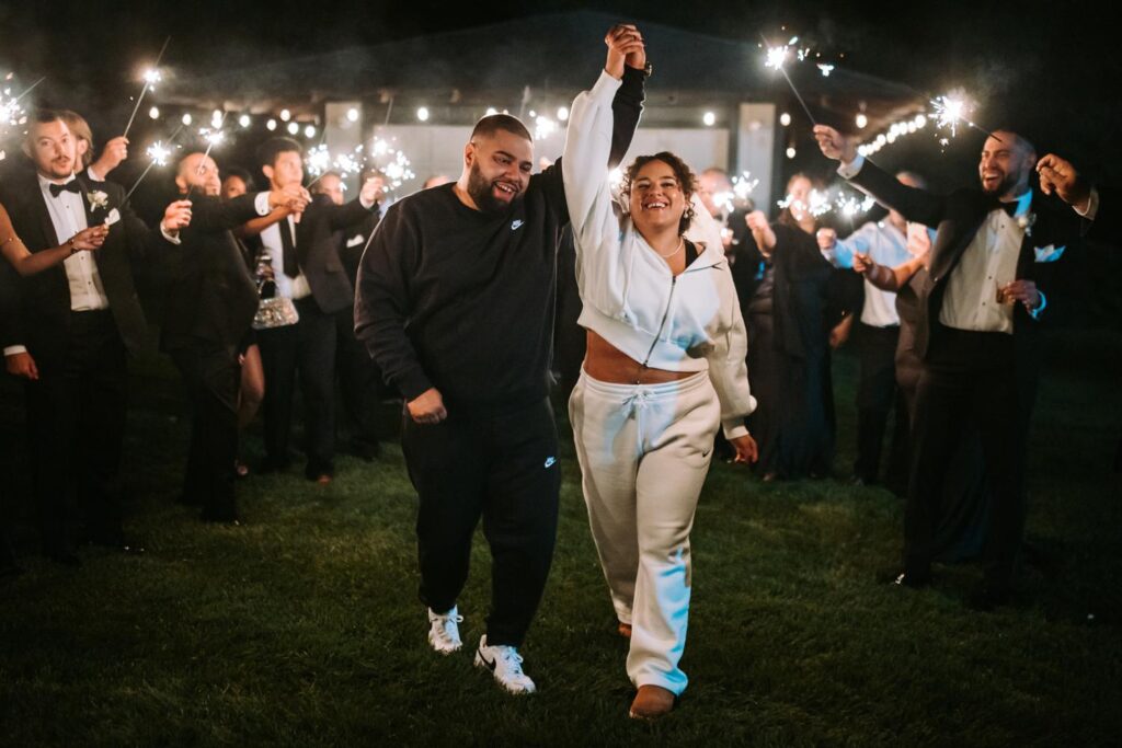 A bride and groom walking down a tunnel of sparklers for the exit at The Hops Company