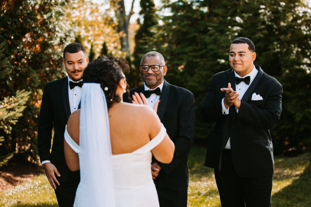 Family members of a bride react to her wearing her wedding dress at The Hops Company