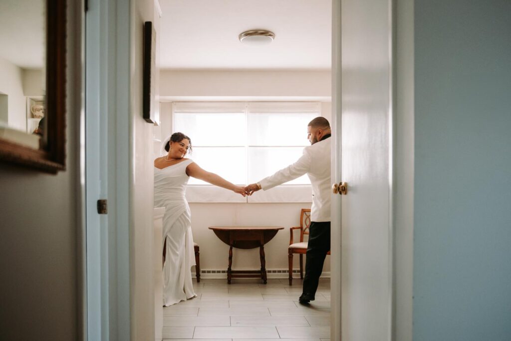 A bride and groom reaching to eachother in the bridal cottage at The Hops Company