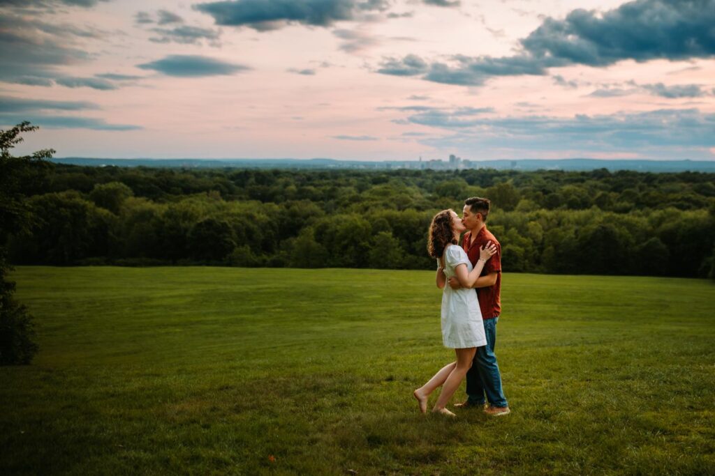 A couple kisses in a large field at Wickham Park in Connecticut