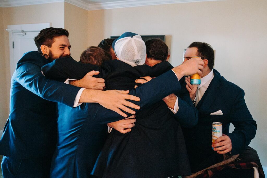 Dominic and groomsmen group hug while getting ready at The Publick House wedding in Sturbridge Massachusetts
