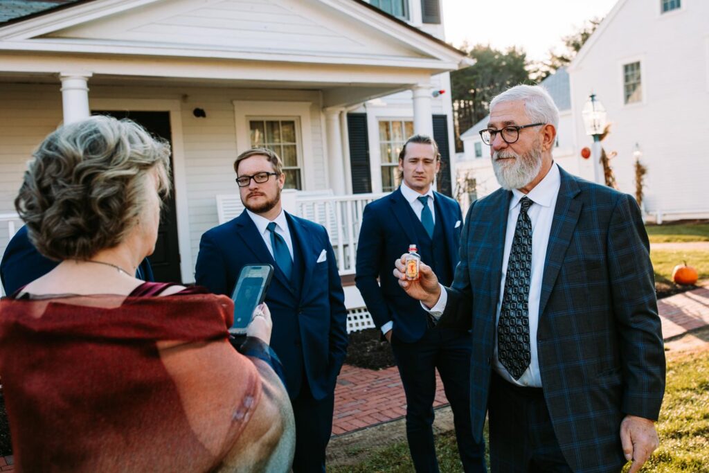 Wedding guests chatting outside the Publick House in Sturbridge before the ceremony, with groomsmen in blue suits gathered on the lawn