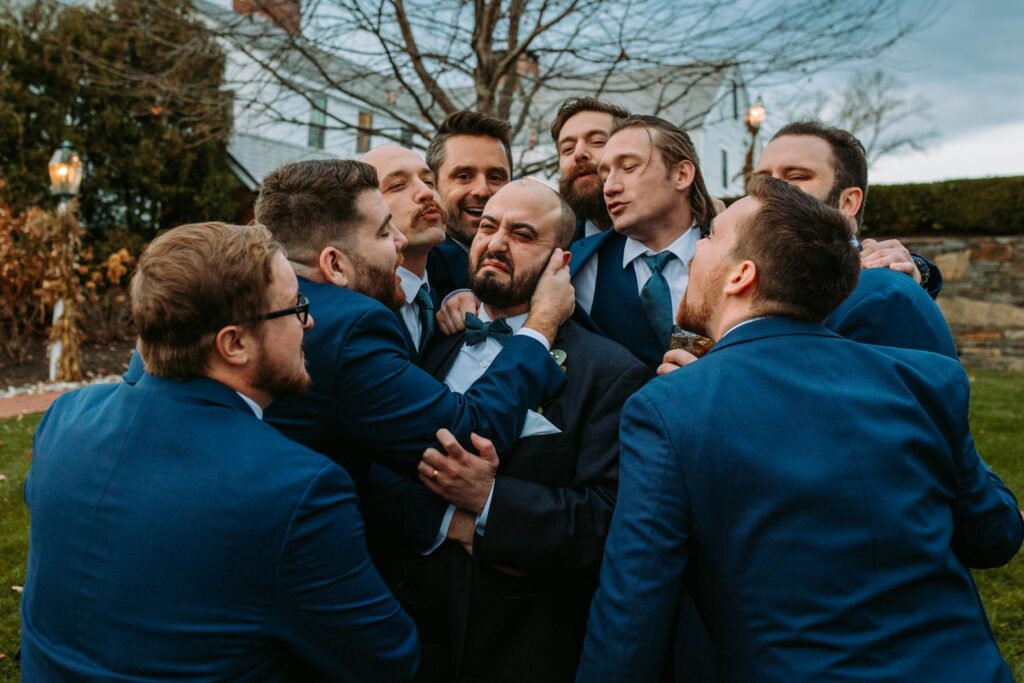 Groom surrounded by cheering groomsmen in blue suits