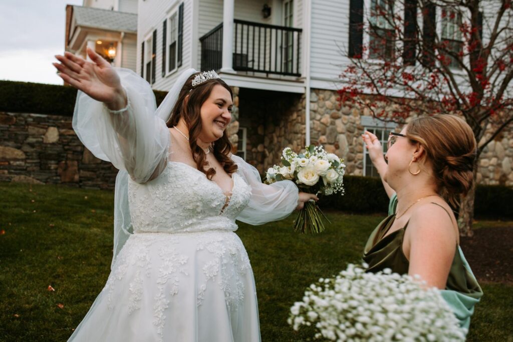 Bride going to hug bridemaid on the lawn outside the Publick House
