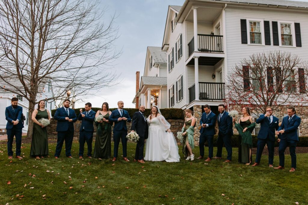 Full wedding party lined up outdoors in front of the historic New England buildings at the Publick House in Sturbridge