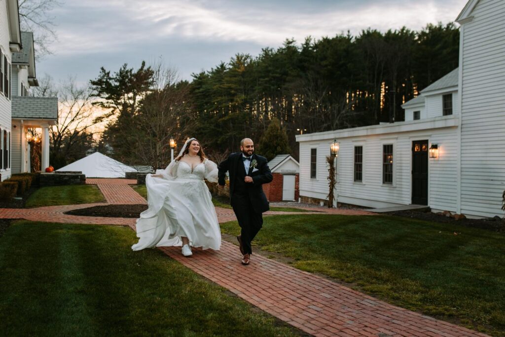 Bride and groom running together along a brick path at the Publick House grounds