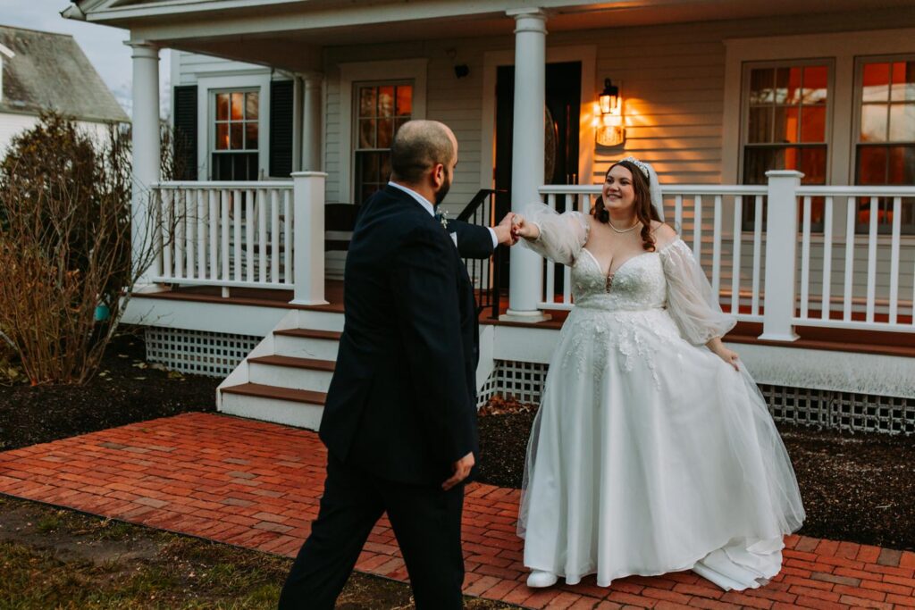 Bride twirling playfully as the groom watches her on a brick patio