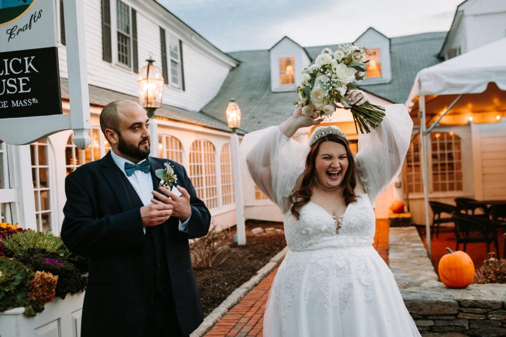 Bride celebrating with her bouquet raised while the groom holds a drink beside her
