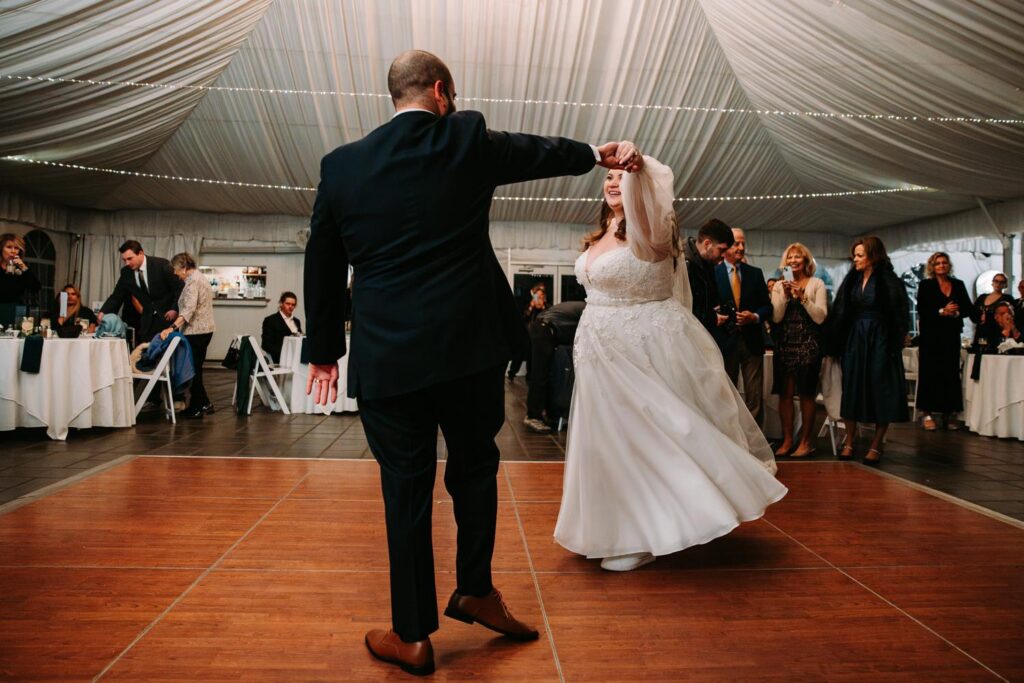 Groom twirling the bride during their first dance inside a tented reception at the Publick House in Sturbridge
