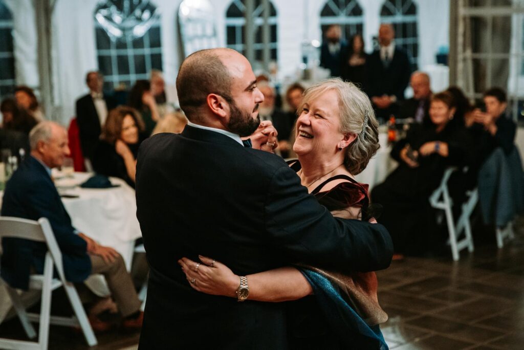 Groom dancing with mom, both smiling and laughing on the dance floor