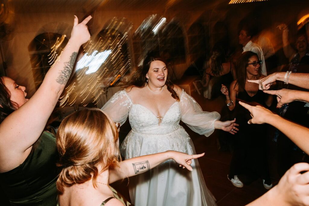 Guests dancing together under warm reception lighting inside the tent