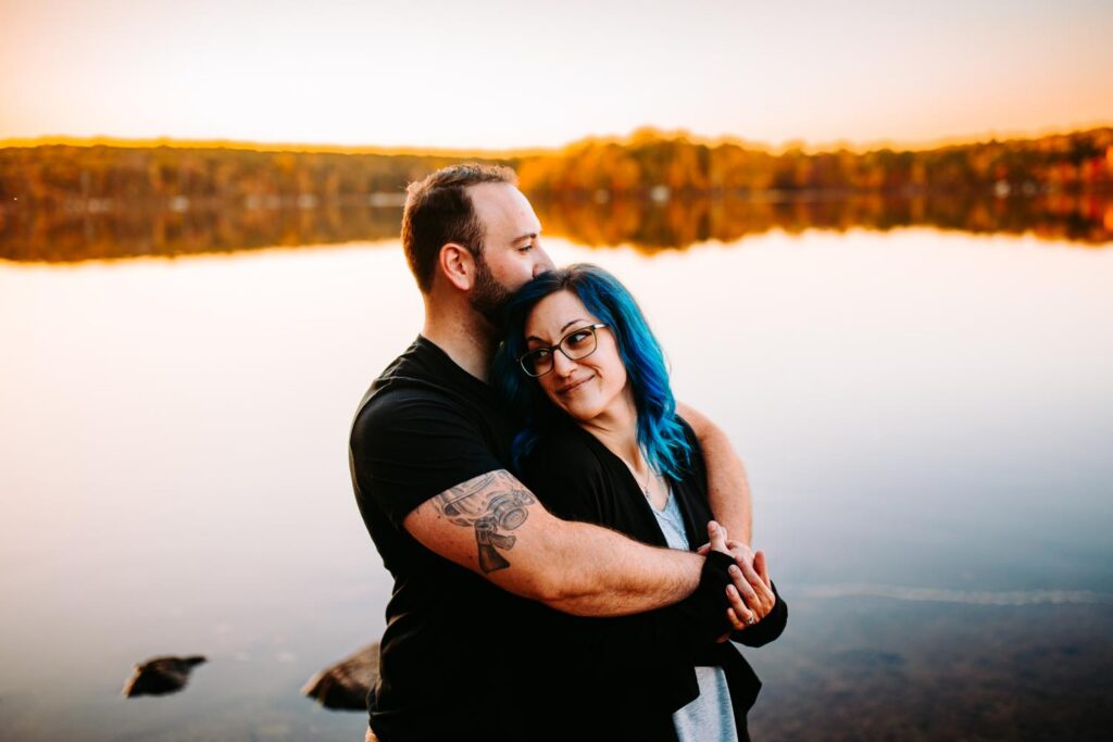 Couple shares a quiet moment during their engagement photos in front of the lake at Lincoln Woods State Park in Rhode Island