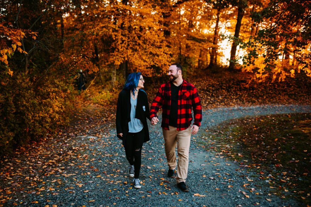 Couple walks hand in hand in the fall foliage at Lincoln Woods State Park in Rhode Island