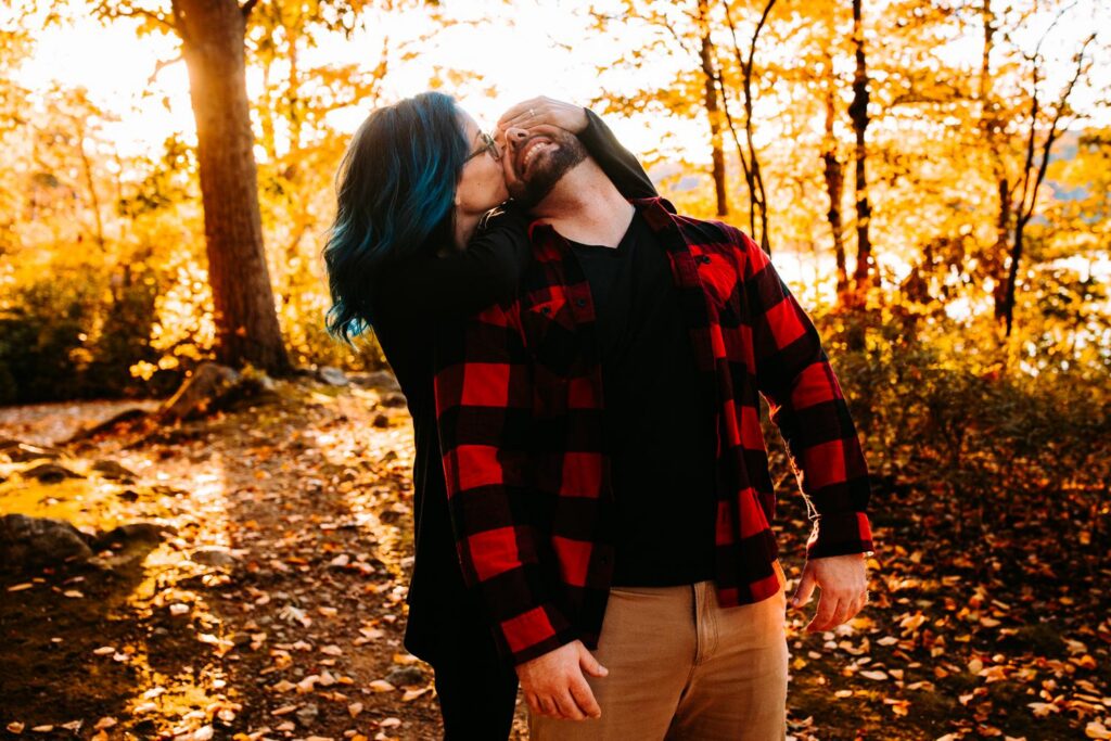 Couple playfully interacts during their fall engagement session at Lincoln Woods State Park in Rhode Island