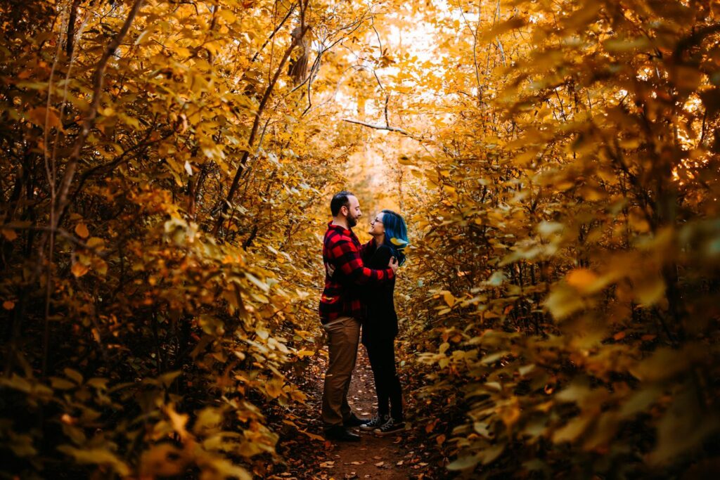 Couple embraces among the October leaves during their engagement session at Lincoln Woods in Rhode Island